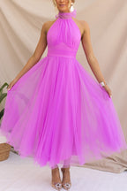 Woman wearing a sleeveless tulle halter midi dress with ruched bodice and full skirt