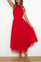 Woman wearing a sleeveless tulle halter midi dress with ruched bodice and full skirt - view 7