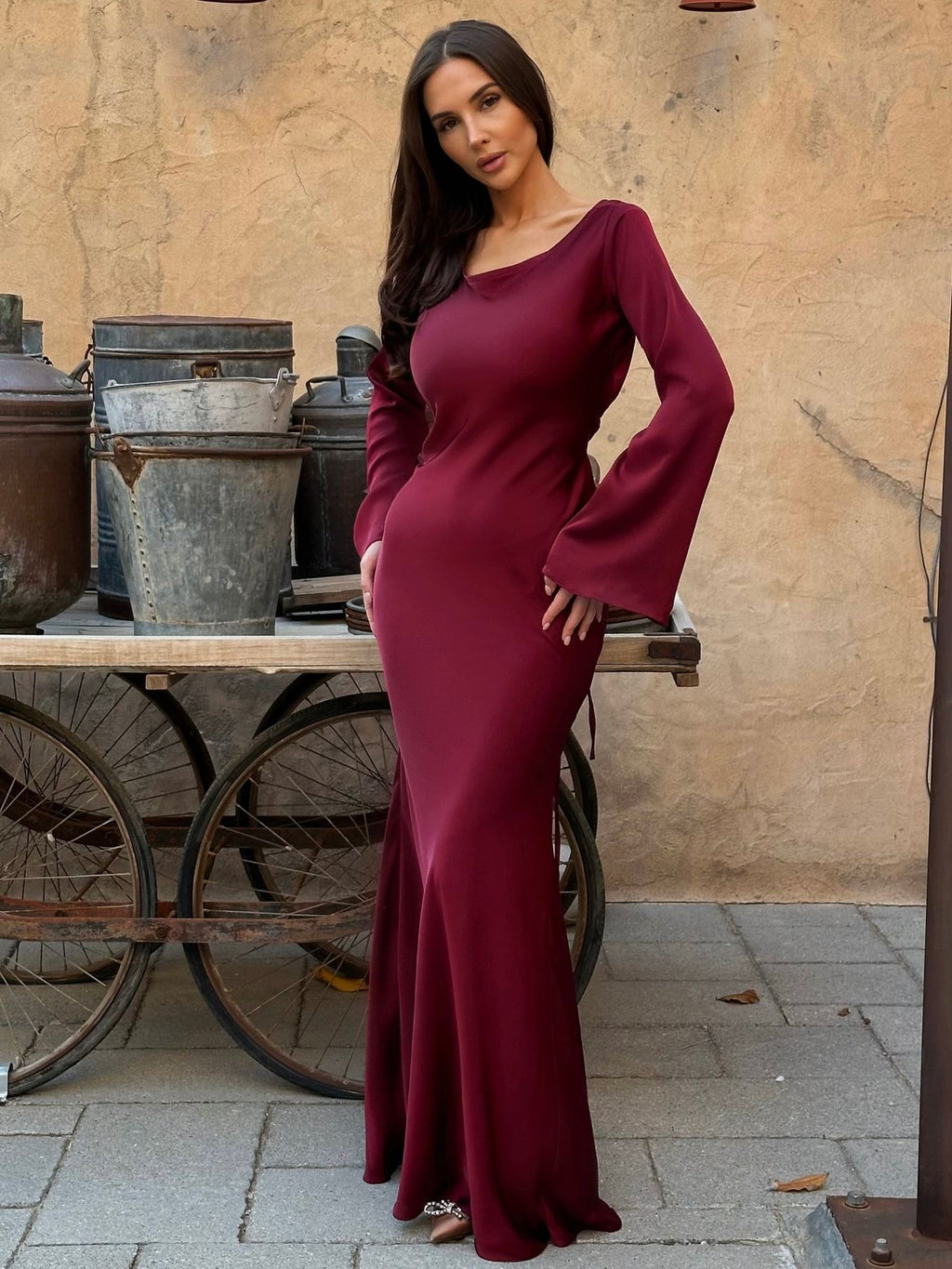 Woman wearing a fitted satin long sleeve maxi dress with bell sleeves and wide scoop neckline - view 18