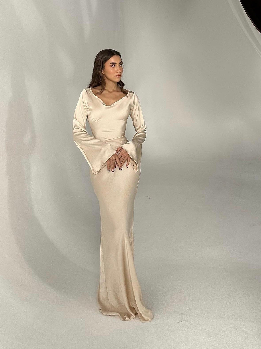 Woman wearing a fitted satin long sleeve maxi dress with bell sleeves and wide scoop neckline - view 7