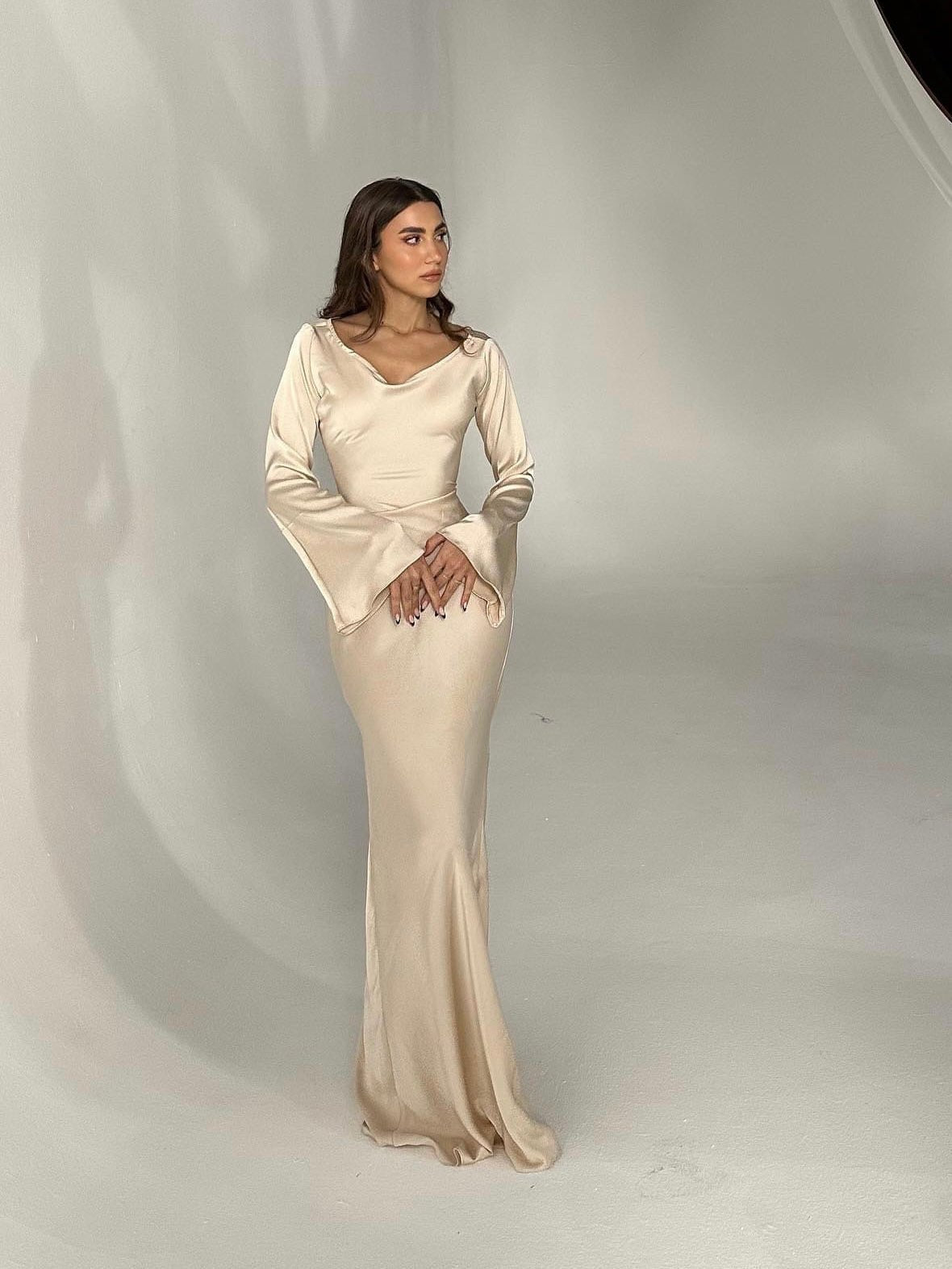 Woman wearing a fitted satin long sleeve maxi dress with bell sleeves and wide scoop neckline - view 7