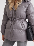 Woman in a brown quilted hooded puffer jacket with drawstring waist - view 18