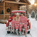 Family in matching red and white striped Christmas pajamas with gray cuffs