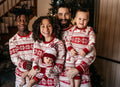 Family wearing matching red and white reindeer and snowflake print Christmas pajamas