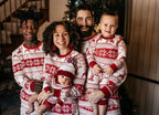 Family wearing matching red and white reindeer and snowflake print Christmas pajamas
