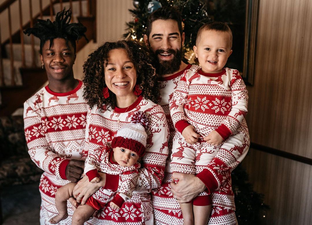 Family wearing matching red and white reindeer and snowflake print Christmas pajamas