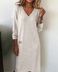 Woman wearing a V-neck long sleeve midi sweater dress with ribbed cuffs and a small patch detail