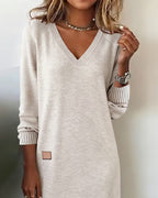 Woman wearing a V-neck long sleeve midi sweater dress with ribbed cuffs and a small patch detail - view 3