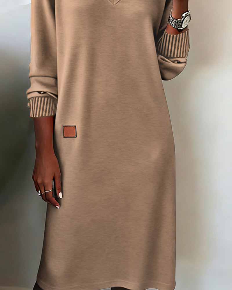Woman wearing a V-neck long sleeve midi sweater dress with ribbed cuffs and a small patch detail - view 9