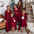 Family wearing matching red and black buffalo plaid Christmas pajamas