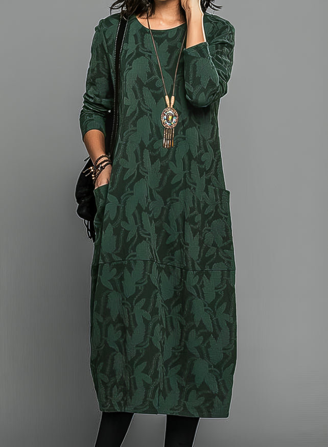 Woman wearing a green leaf jacquard long sleeve midi dress with patch pockets and crew neck