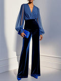 Model in a blue velvet evening jumpsuit with wide legs and sheer balloon sleeves