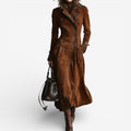 Woman wearing a long double breasted suede-look trench coat with contrast piping and flap pockets