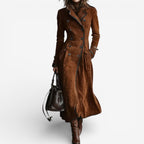 Woman wearing a long double breasted suede-look trench coat with contrast piping and flap pockets