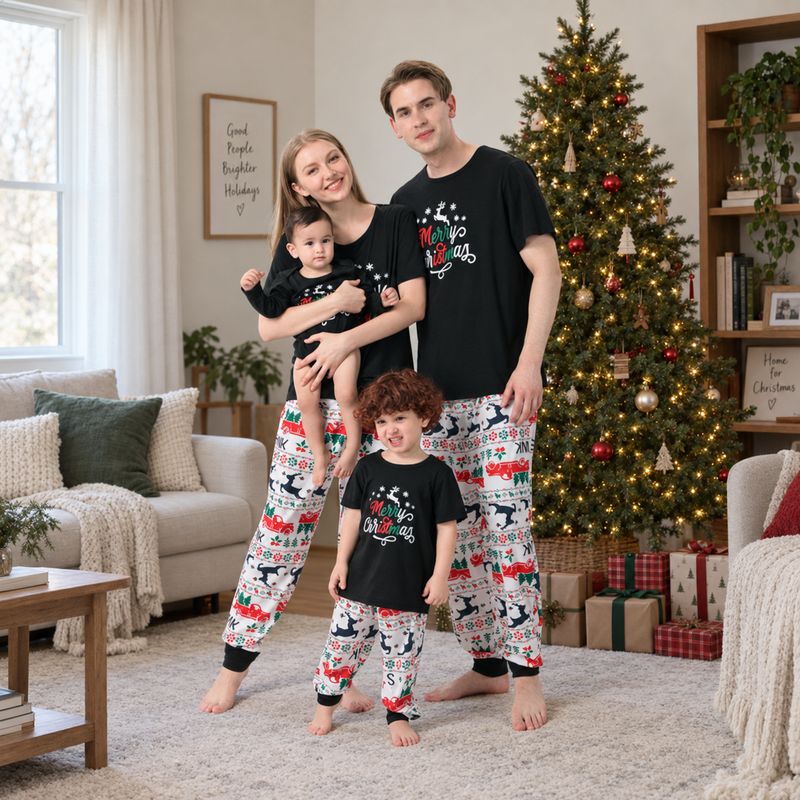 Family wearing matching black Merry Christmas tees and reindeer print jogger pajamas by a Christmas tree