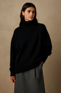 Woman wearing an oversized roll neck sweater in a soft brushed knit with ribbed cuffs