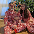 Family wearing matching red and white reindeer print Christmas pajamas by the tree - view 2