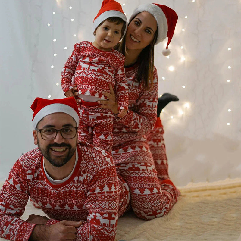 Family wearing matching red and white reindeer print Christmas pajamas by the tree - view 4