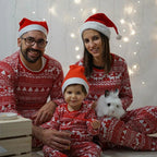 Family wearing matching red and white reindeer print Christmas pajamas by the tree - view 5