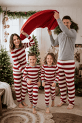 Family wearing matching red and white striped Christmas pajamas with gray trim