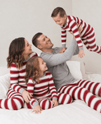 Family wearing matching red and white striped Christmas pajamas with gray trim - view 3