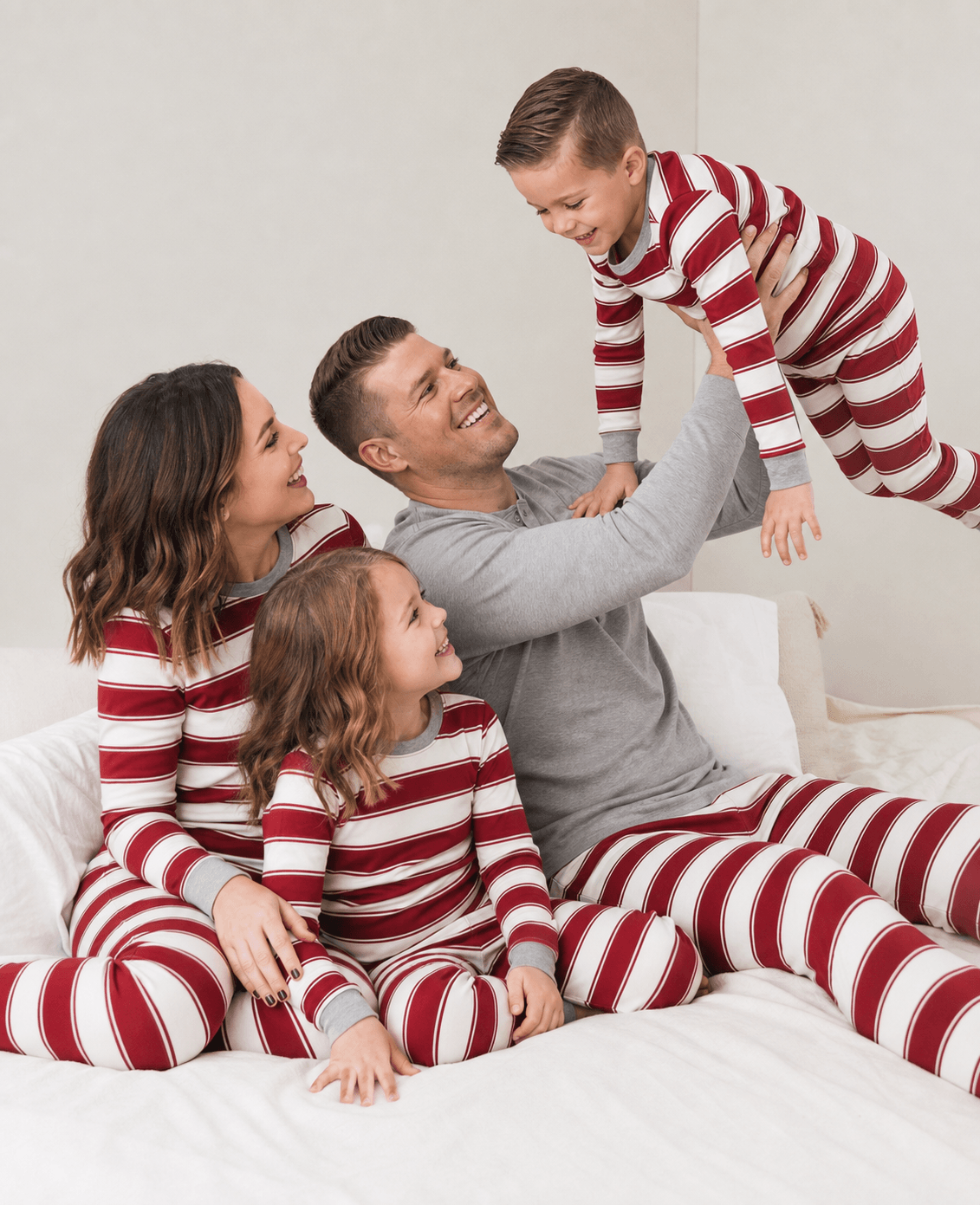 Family wearing matching red and white striped Christmas pajamas with gray trim - view 3