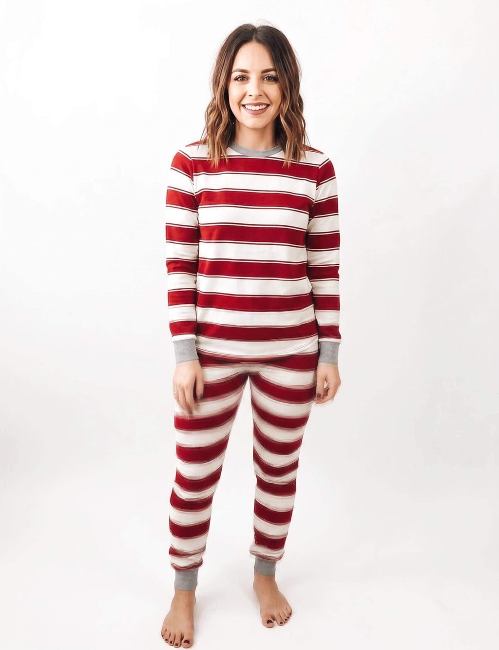 Family wearing matching red and white striped Christmas pajamas with gray trim - view 9