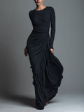 Model in a black formal evening maxi dress with long sleeves and draped skirt