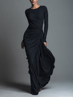 Model in a black formal evening maxi dress with long sleeves and draped skirt